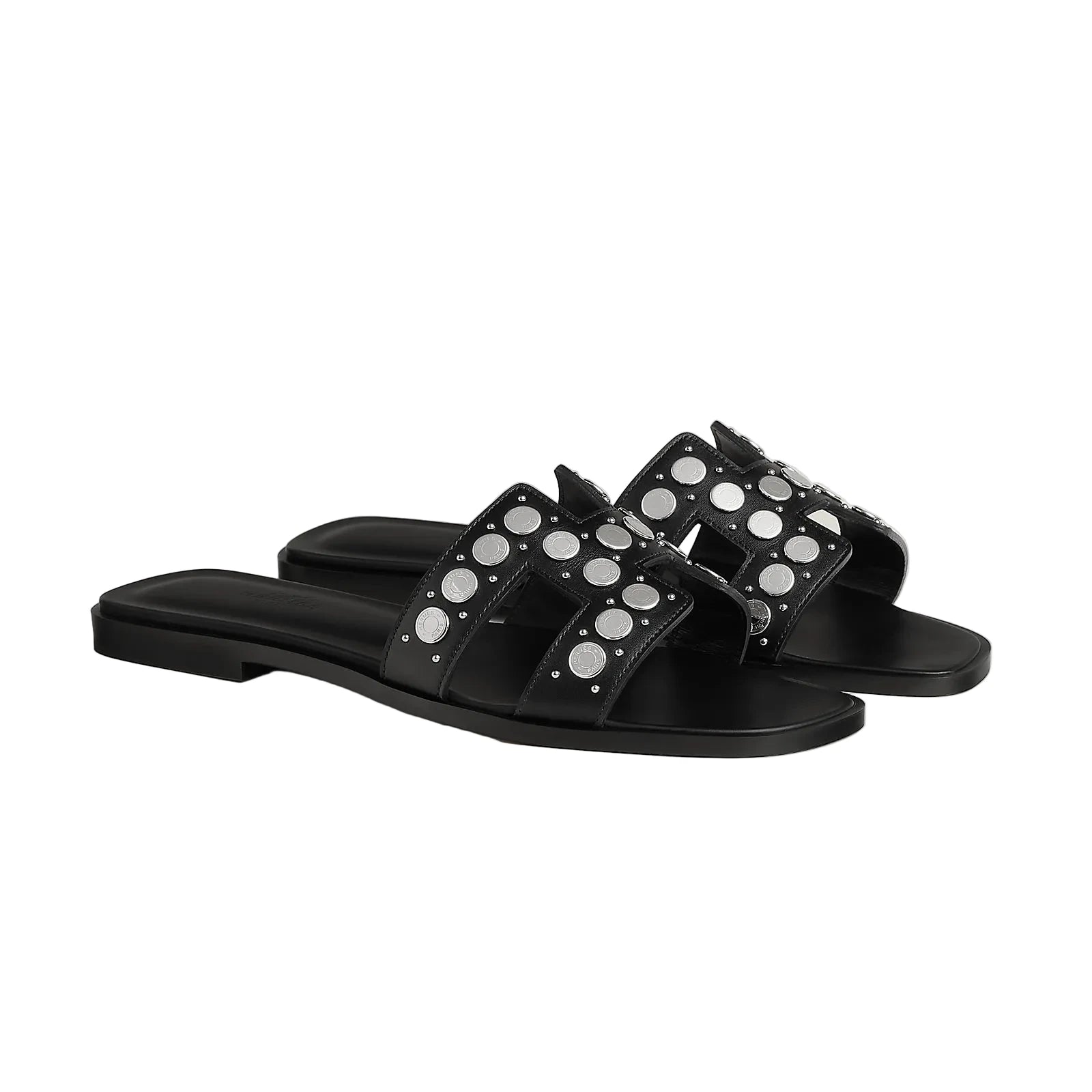 Black sandals with silver studs on a light gray background