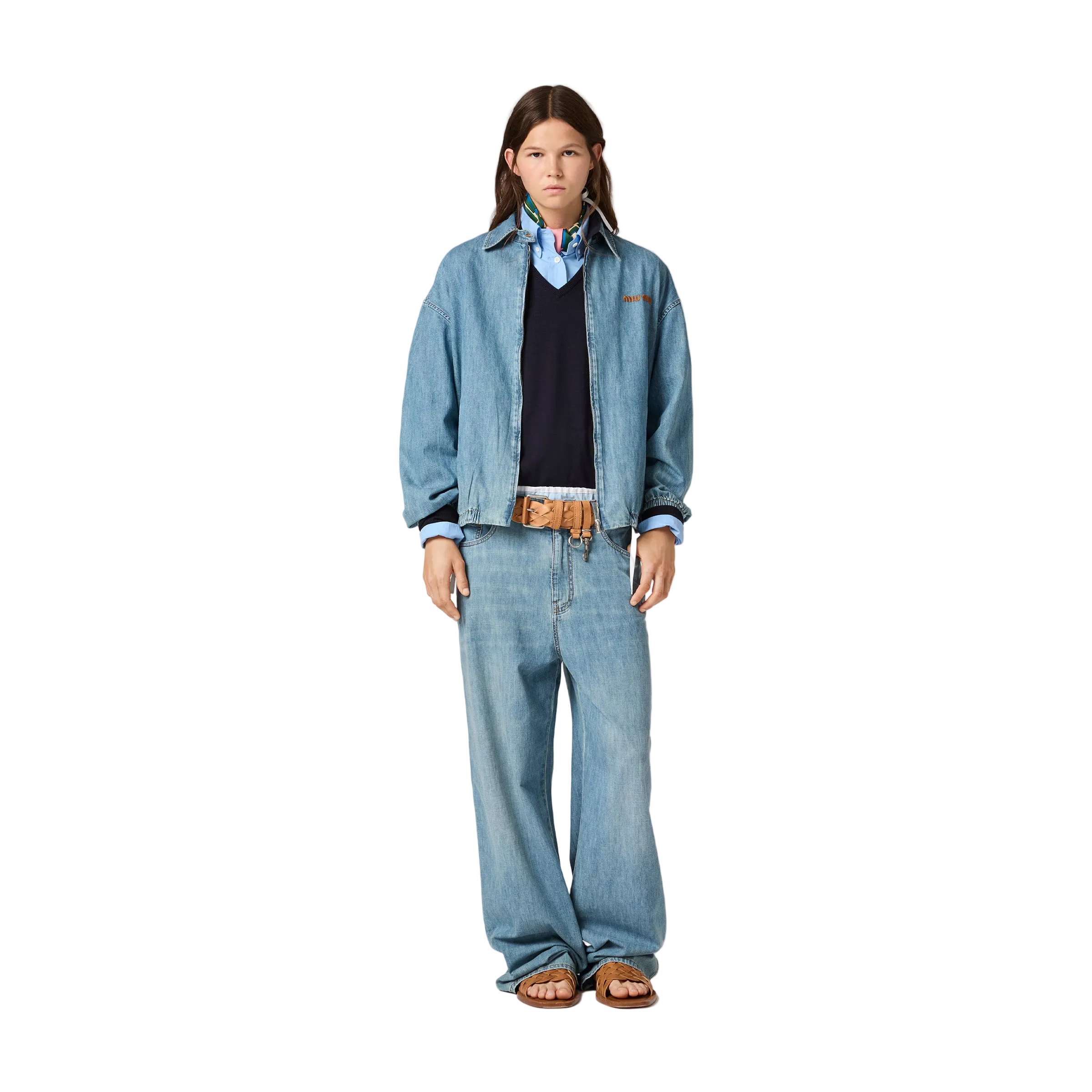 Person wearing a denim jacket and jeans on a beige background