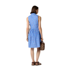Woman wearing a blue dress with a subtle pattern, holding a small bag, on a plain background