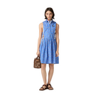 Woman wearing a blue sleeveless dress with a pattern, holding a brown handbag on a beige background