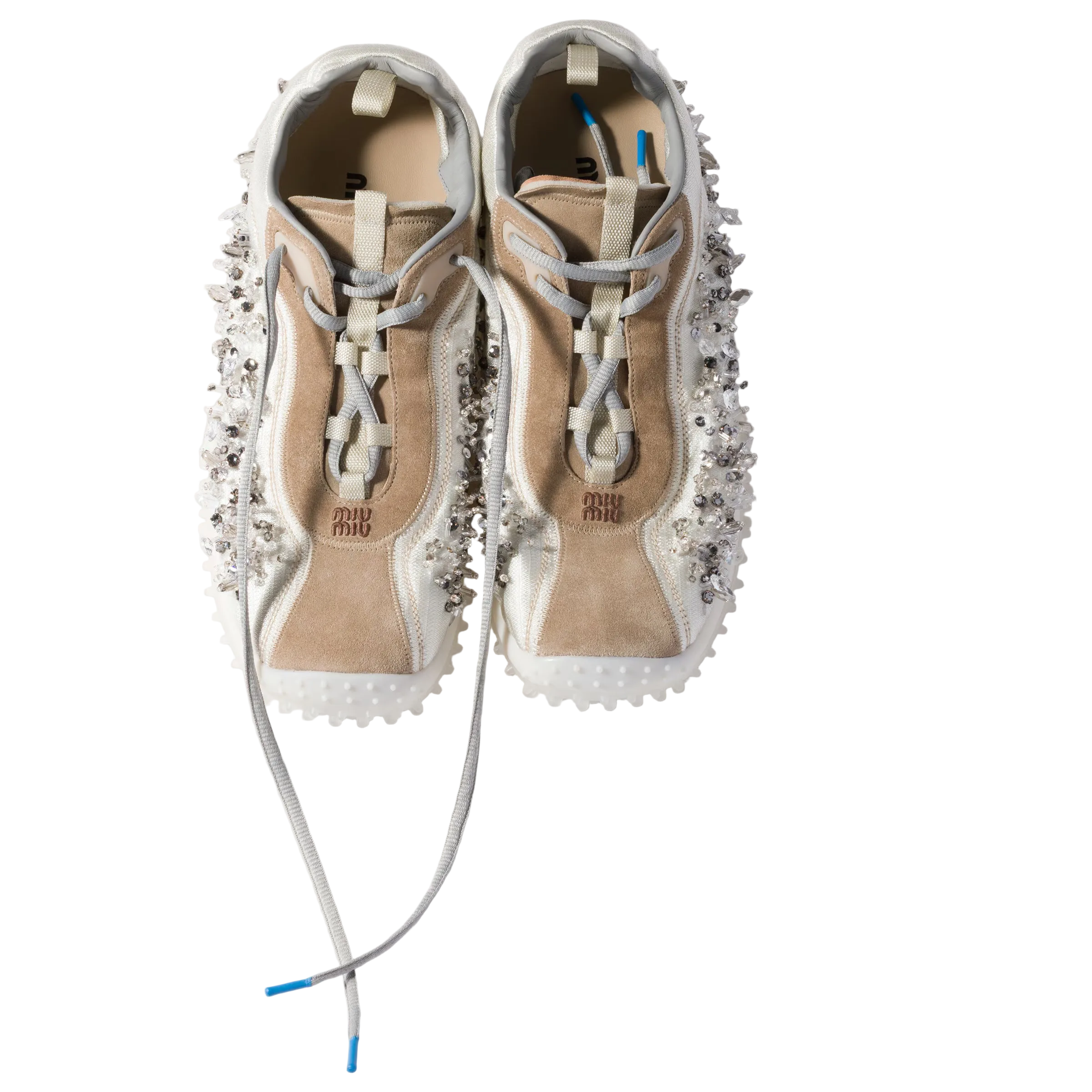 A pair of chunky platform sneakers with beige suede panels, white mesh sides, and heavy silver rhinestone embellishments, shown from a top-down angle on a light beige background.