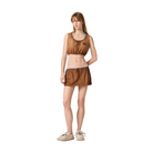 Woman wearing a brown sleeveless top and skirt set on a beige background